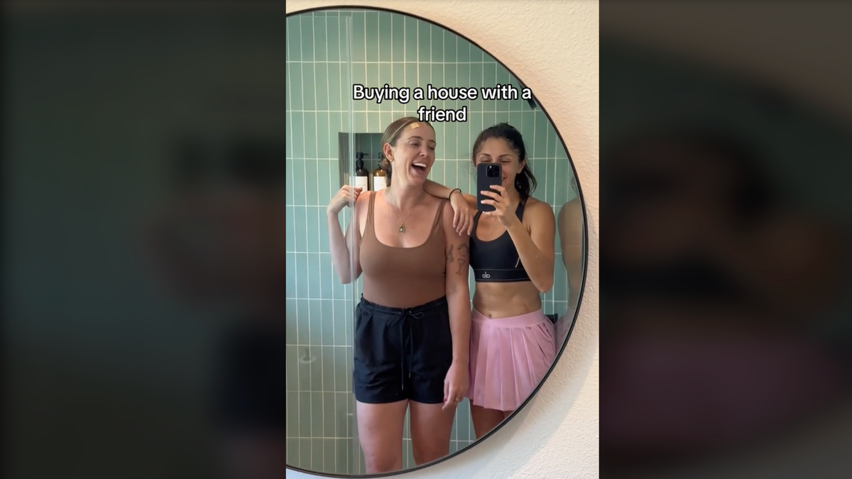 Two women take a selfie in a mirror during a TikTok video